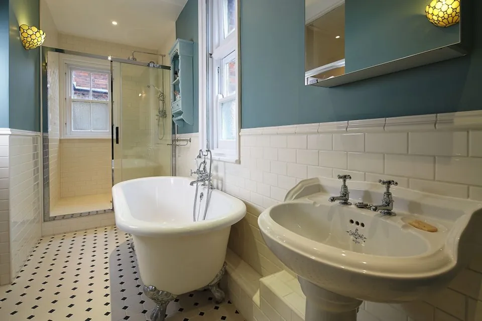 Shower with a single sliding glass door beside a roll-top bath