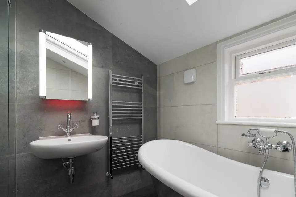 Loft bathroom with a slipper bath and illuminated mirror