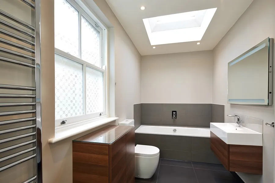 Bathroom with a walnut vanity, skylight and towel radiator