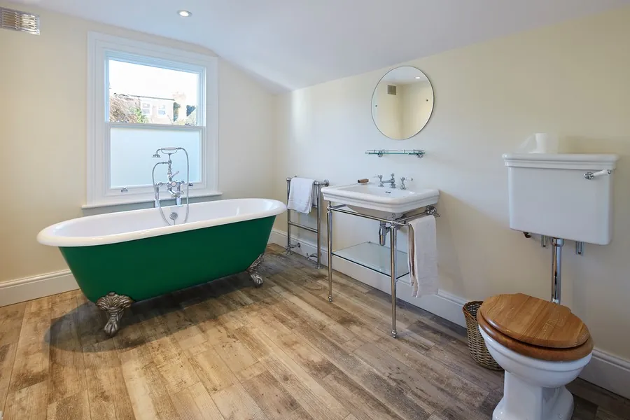 Green roll-top bath on timber floor with a washstand